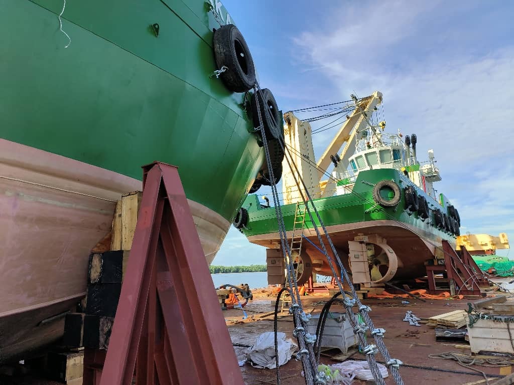 Heavy lift tug boats loaded on heavy lift vessel for transit.